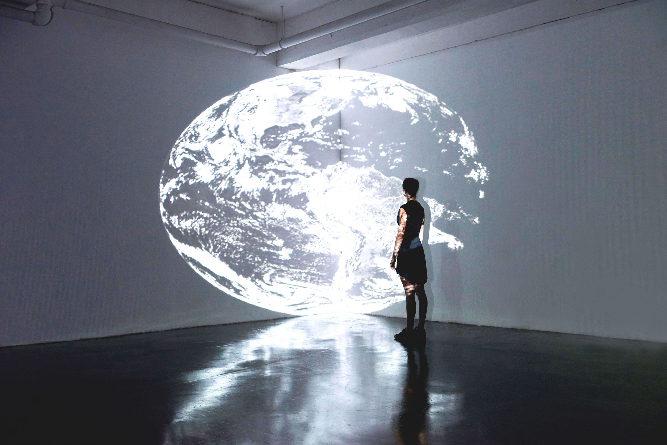 A person standing before a large illuminated image of the Earth