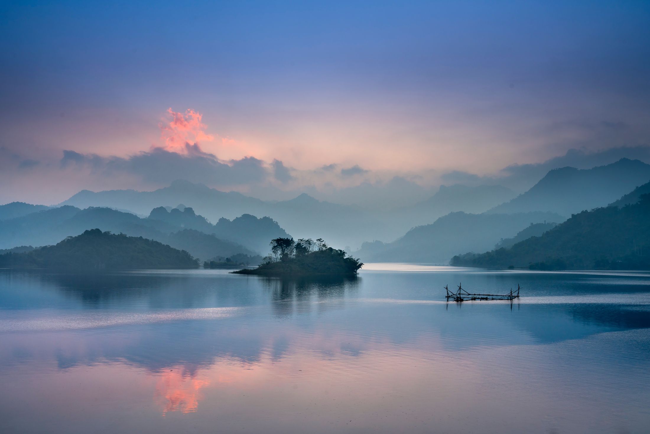 Mountains and an island reflected in a still lake at dawn